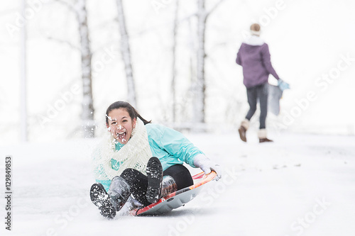 Canvastavla Two young girls sledding down hill in ice and snow