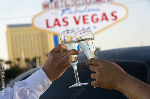 Photography Hands toasting white wine with car and signboard in the background