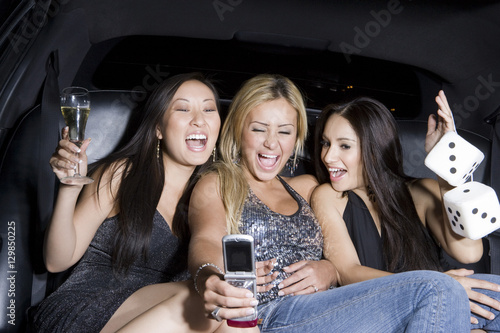 Happy female friends in limousine taking self portrait through mobile phone