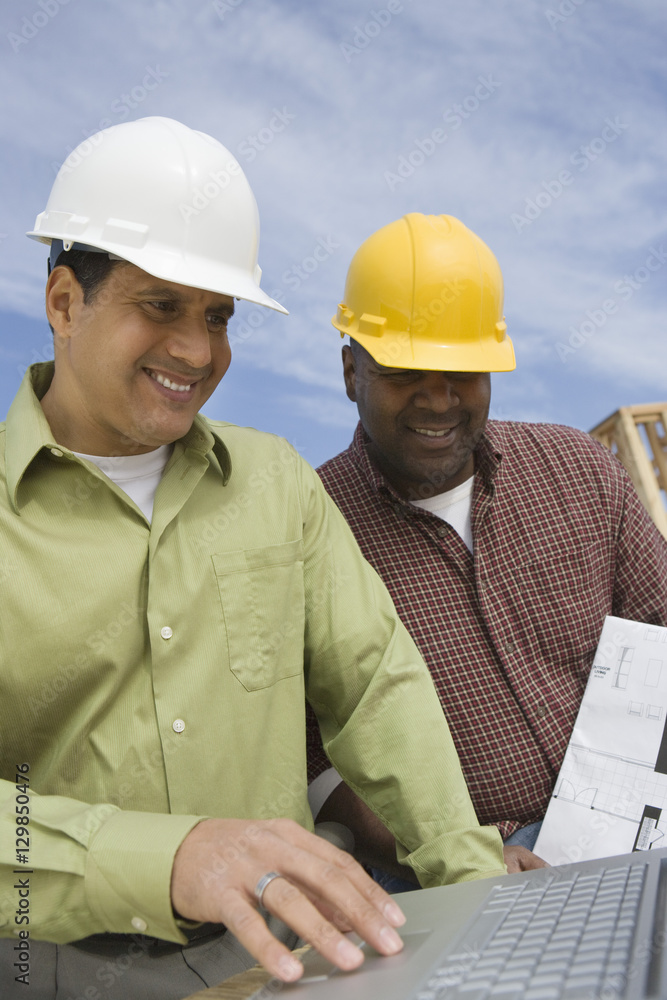 Architect and foreman in discussion while using laptop Architect and foreman in discussion while using laptop