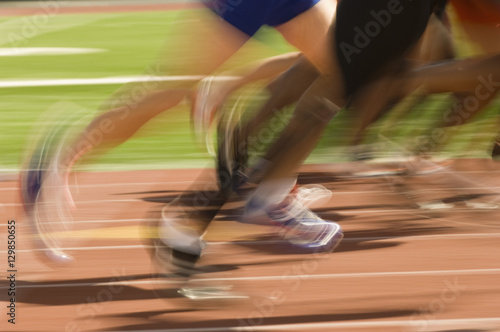 Blurred motion of male athletes racing on track and field