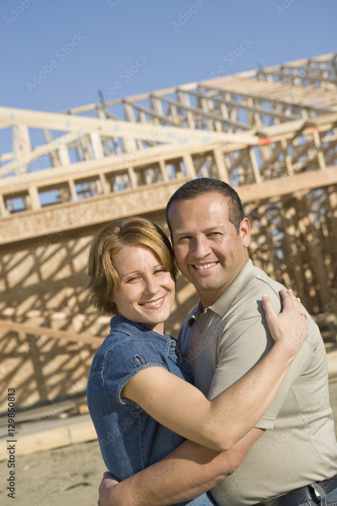Portrait of happy mature couple embracing in front of incomplete house