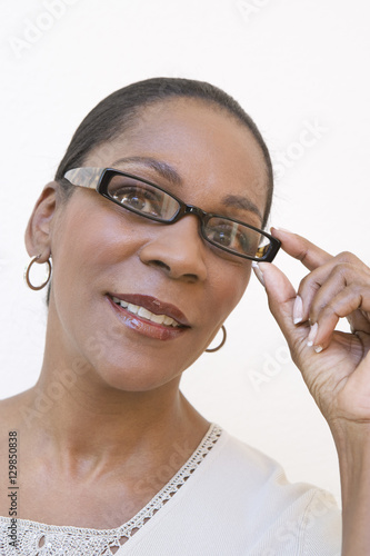 Portrait of an African American senior woman adjusting glasses on white background