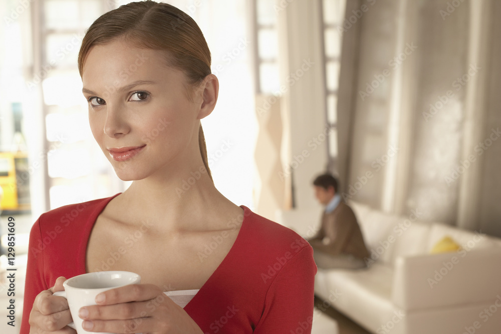 Portrait of confident businesswoman holding coffee cup in office lobby