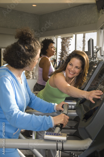 Happy mature trainer looking at senior woman in gym