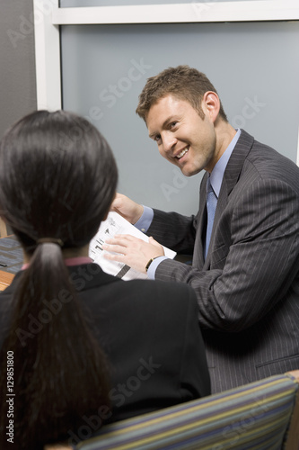 Happy businessman holding blue print and discussing with business woman in office