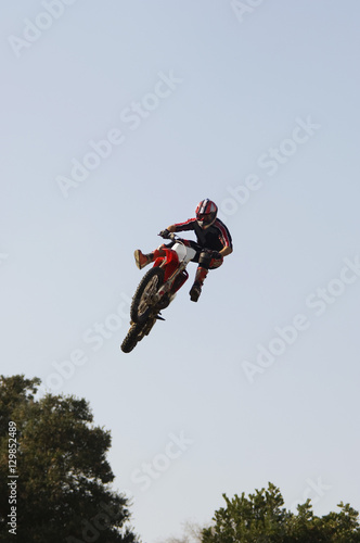 Low angle view of male rider on a motorcycle flying through the air against the sky