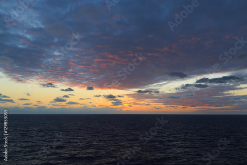 Colorful sunset in ocean with pink clouds.