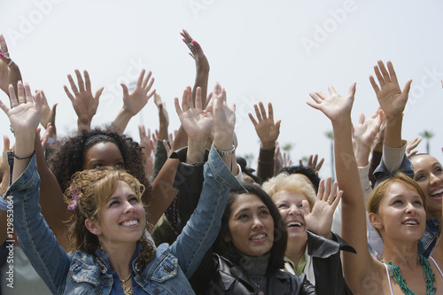 Group of multiethnic women raising hands against clear sky © moodboard