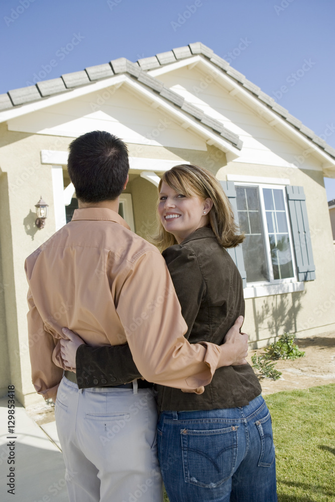 Portrait of happy middle aged woman with man standing in front of a new house