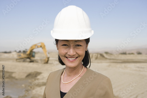 Portrait of a mature female architect wearing hardhat in front of construction site