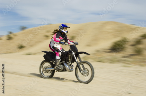 Female off road biker riding the motor bike with speed on a race track