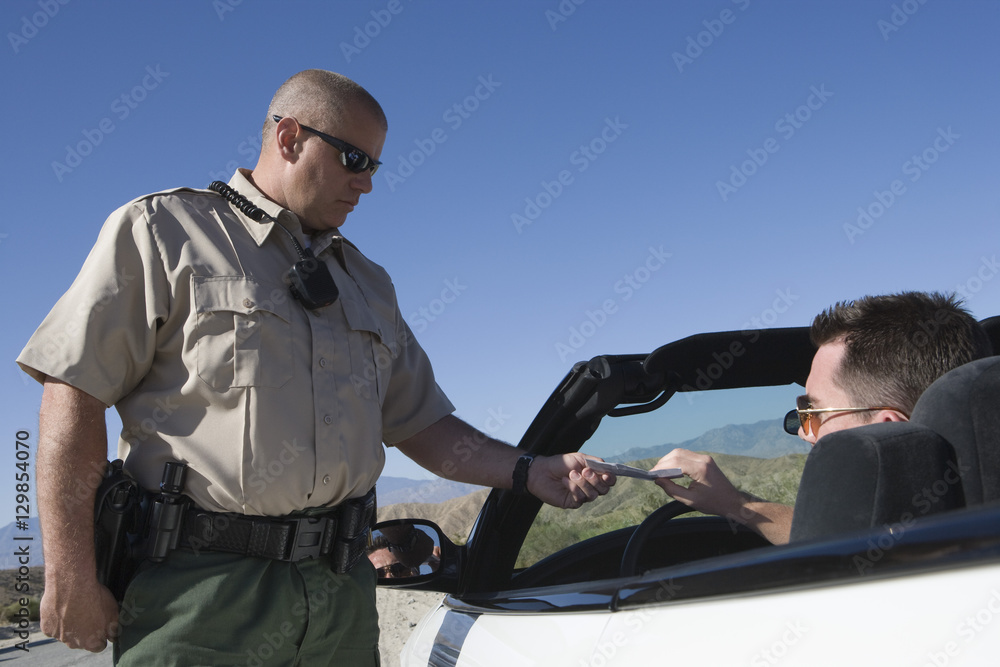 Mature traffic officer checking middle aged man's license