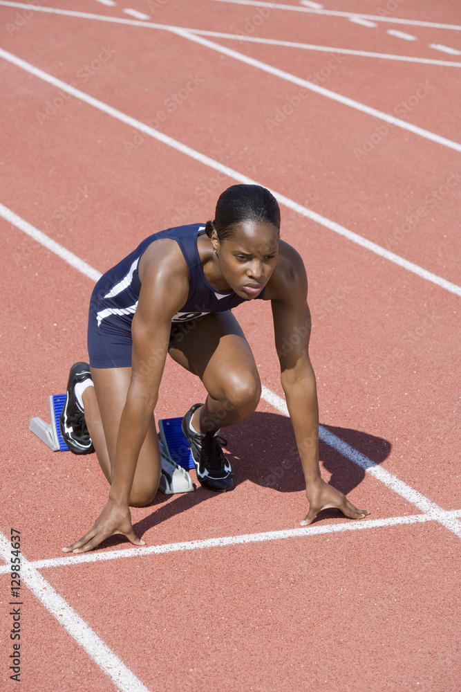 Obraz premium Full length of African American female athlete at starting line on running track