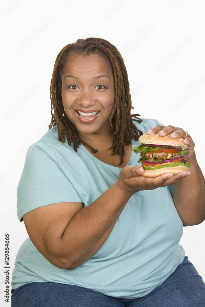 Portrait of an African American woman holding hamburger isolated over white background Portrait of an African American woman holding hamburger isolated over white background