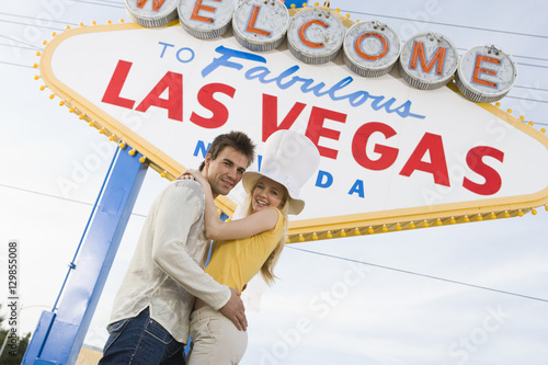 Photography Low angle view of happy couple embracing each other with sign in the background