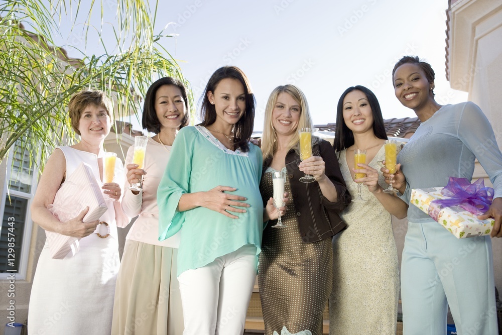 Portrait of happy pregnant woman with female friends holding drinks