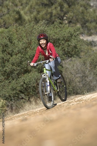 Young Asian female riding bicycle on dirt road