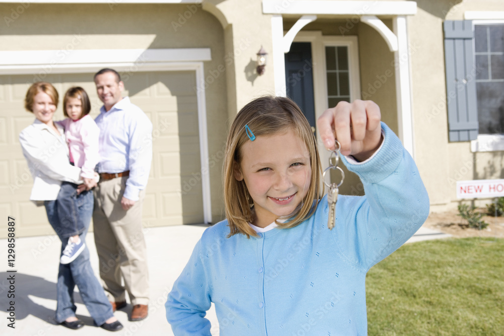 Obraz premium Portrait of happy girl with family holding key in front of new house