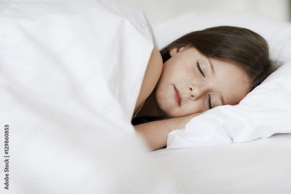 Closeup of young girl sleeping in bed cover with white blanket