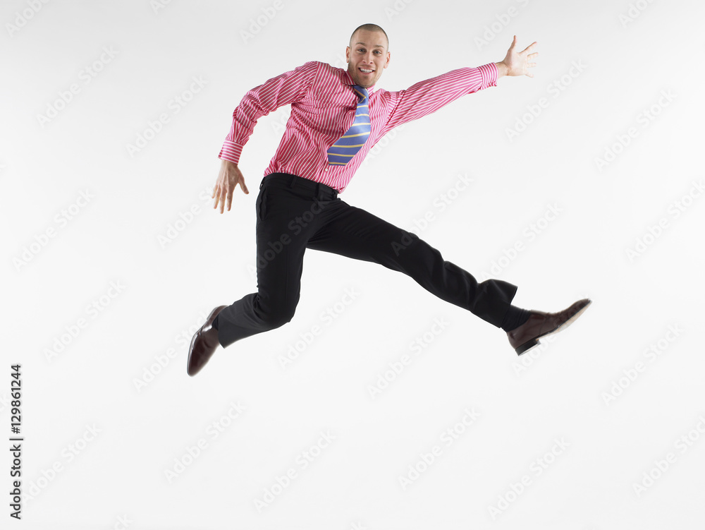 Full length portrait of a bald businessman jumping against white background
