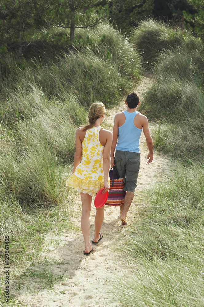 Rear view of a young couple walking on beach trail