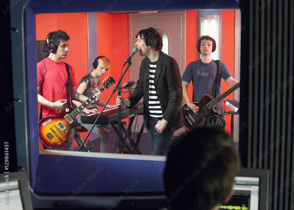Band in recording studio with technician in foreground Band in recording studio with technician in foreground