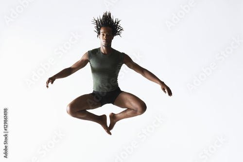 Full length of African American male ballet dancer jumping isolated on white background