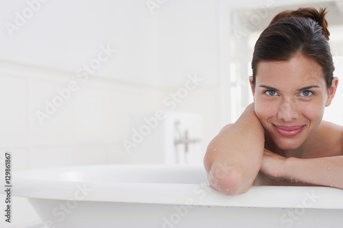 Closeup portrait of a smiling young woman relaxing in bathtub
