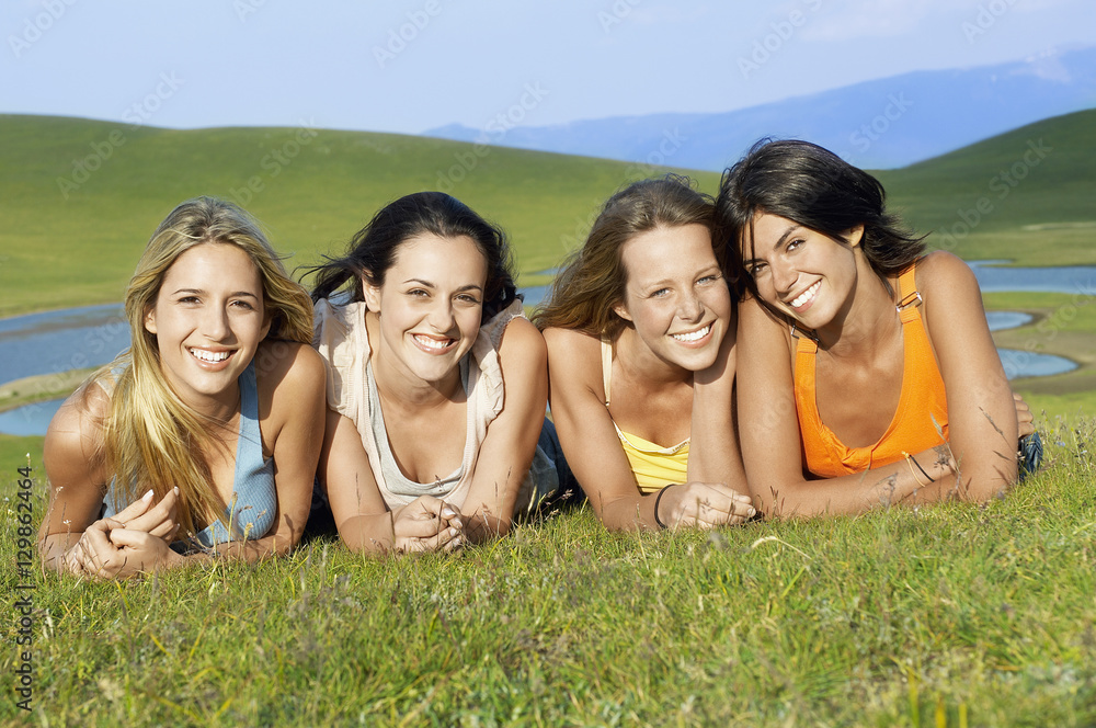 Portrait of happy female friends lying together on grass in park Portrait of happy female friends lying together on grass in park