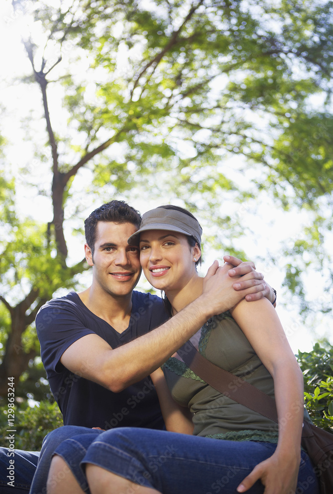 Naklejka premium Portrait of romantic young man embracing woman at park