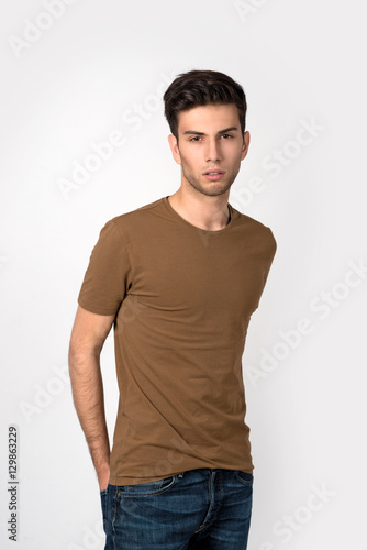  the young man in a shirt and jeans looks at camera.