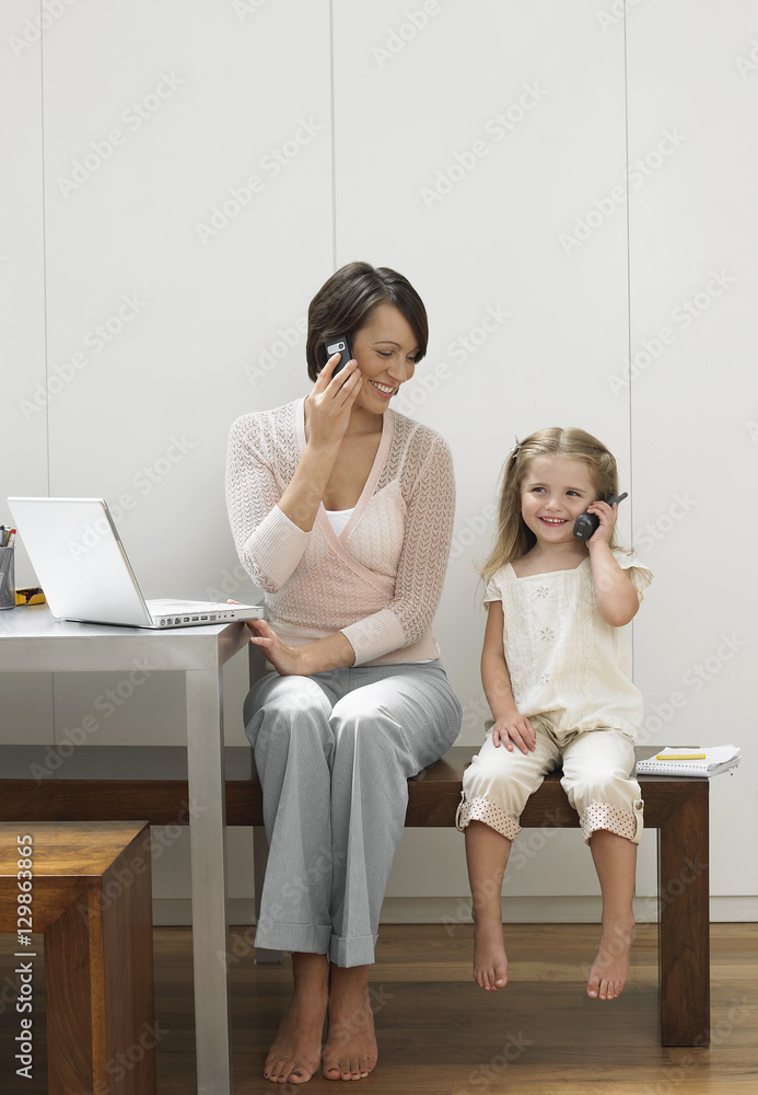 Full length shot of a happy mother and daughter using cellphones Full length shot of a happy mother and daughter using cellphones
