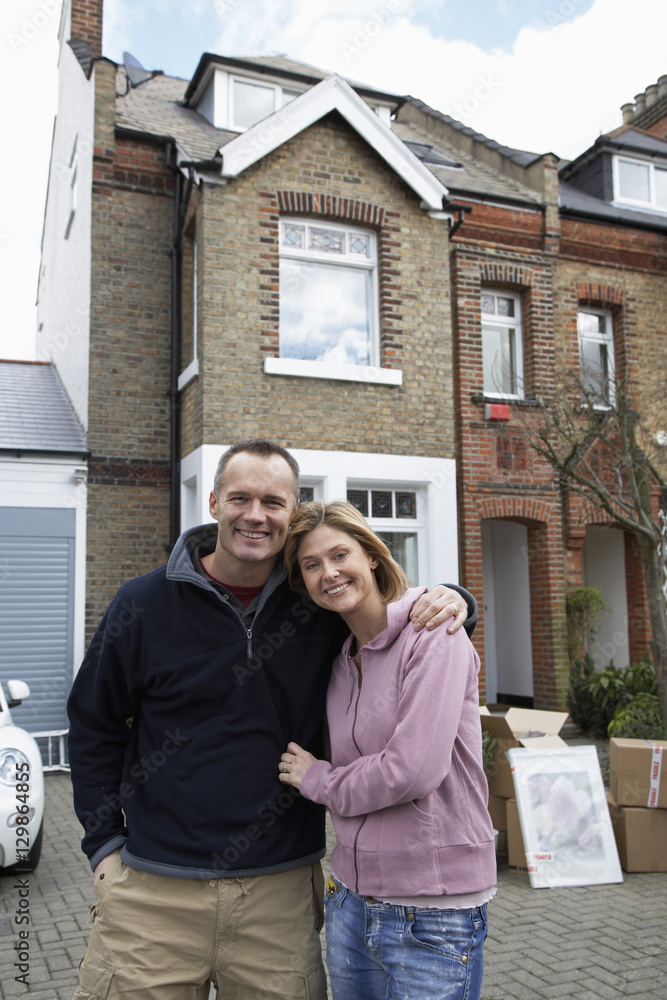 Portrait of a happy couple embracing in front of house