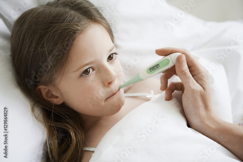 Closeup of little girl with thermometer in mouth