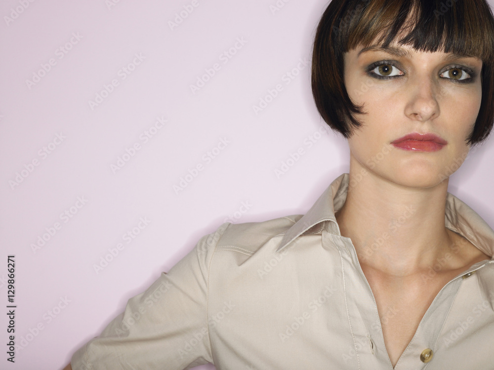 Closeup portrait of a bobbed haired young woman against pink background Closeup portrait of a bobbed haired young woman against pink background