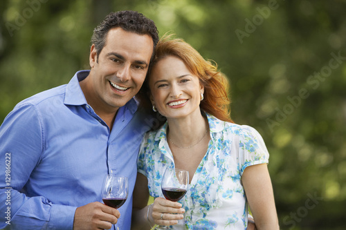 Portrait of smiling couple holding wine glasses in park