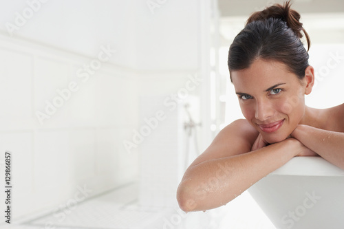 Closeup portrait of a smiling young woman relaxing in bathtub