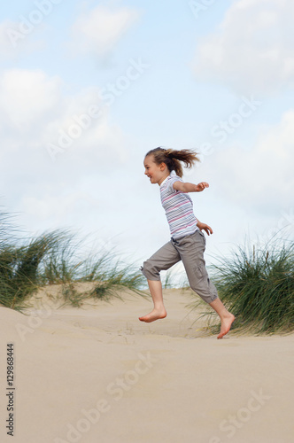 Full length side view of a young girl running on sand at beach © moodboard
