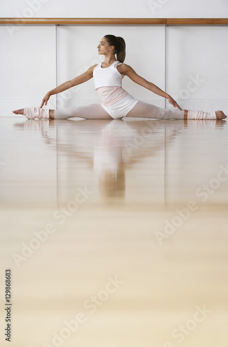 Full length of young ballerina doing split in rehearsal room