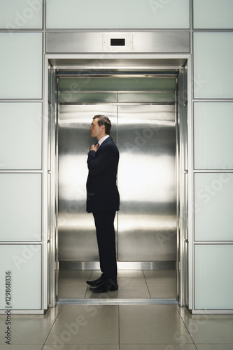 Profile shot of middle aged businessman adjusting necktie in elevator preparing for interview