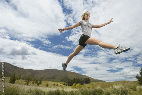 Low angle view of a young woman leaping on rural landscape
