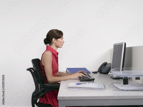 Side view of a female office worker using computer at desk in office photo