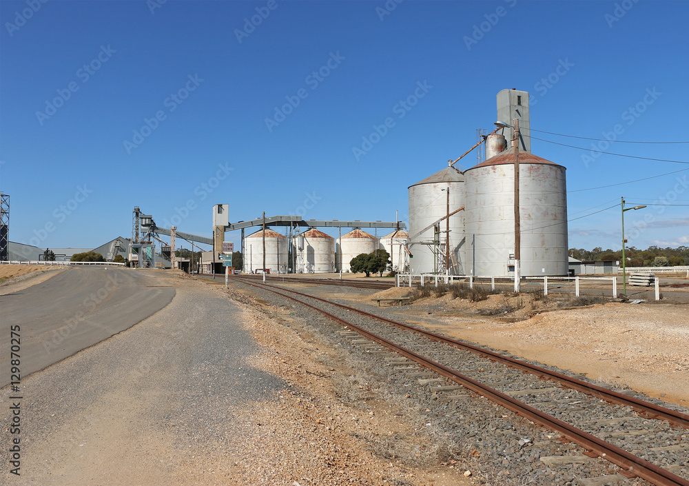 Obraz premium railway tracks and wheat silos against a bright blue sky