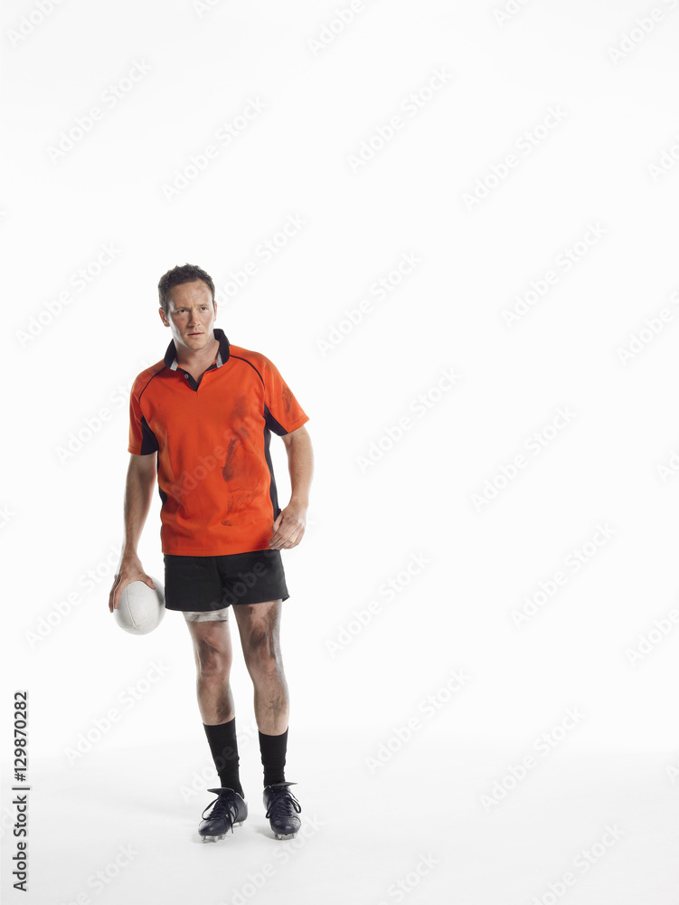 Full length portrait of a rugby player holding ball against white background