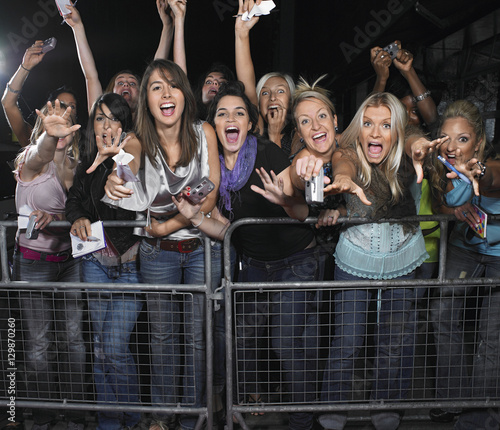фотографія Fans leaning over barrier and screaming