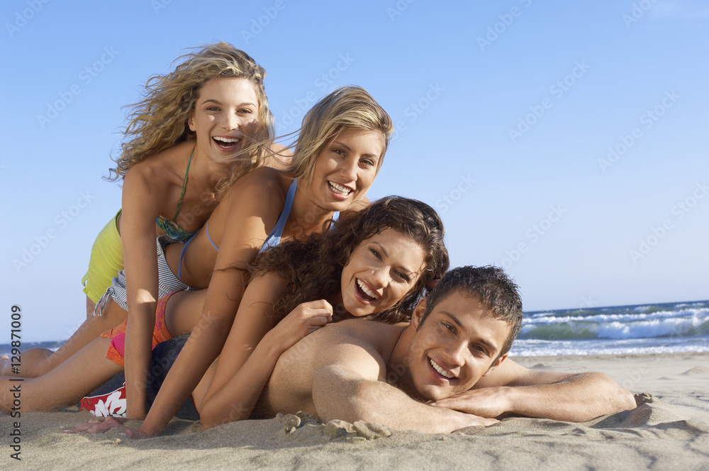 Portrait of happy friends lying on each other at beach