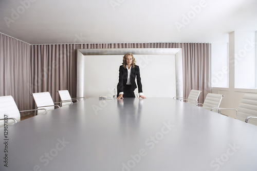 Female business executive standing alone in boardroom