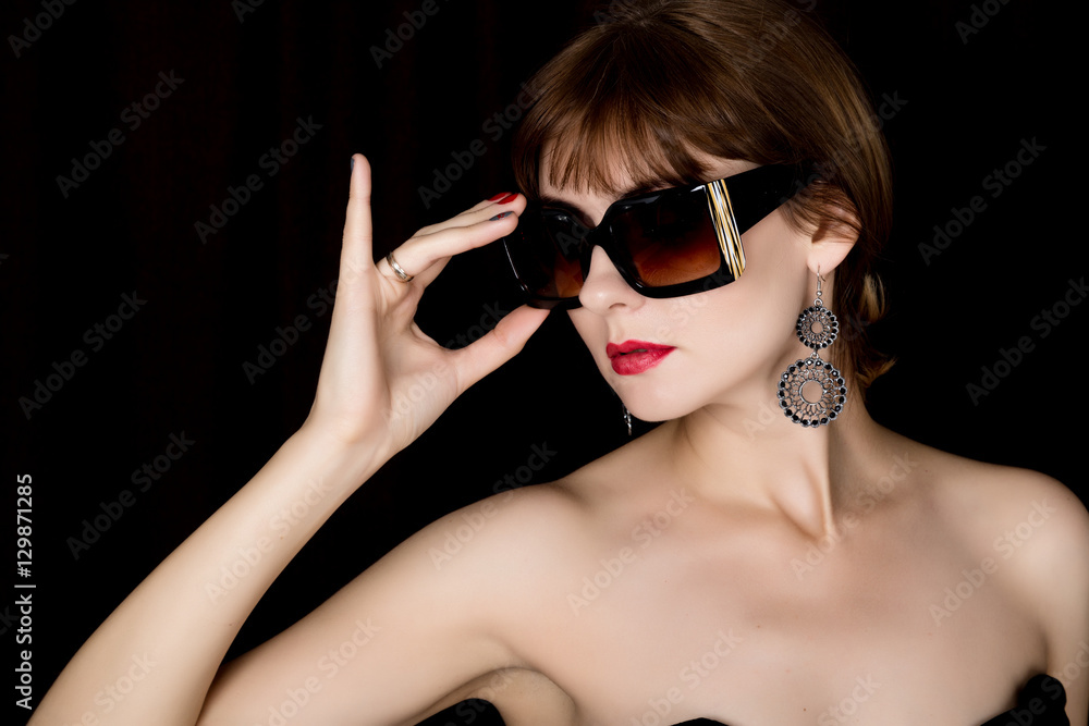 Beauty retro female model with professional makeup in a long leather gloves, holding over size sunglasses Beauty retro female model with professional makeup in a long leather gloves, holding over size sunglasses