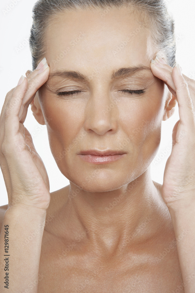 Closeup of stressed middle aged woman rubbing temples on white background Closeup of stressed middle aged woman rubbing temples on white background